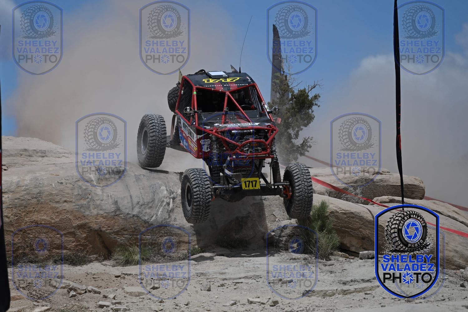 Off-road car dropping off a rock ledge through the dust