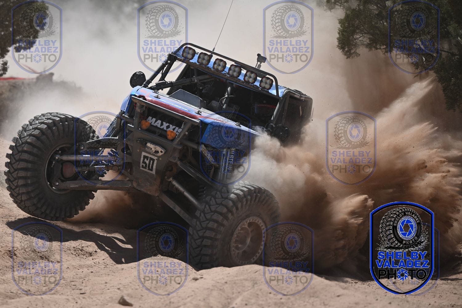 Blue Ultra4 car number 50 throwing a huge rooster tail of sand