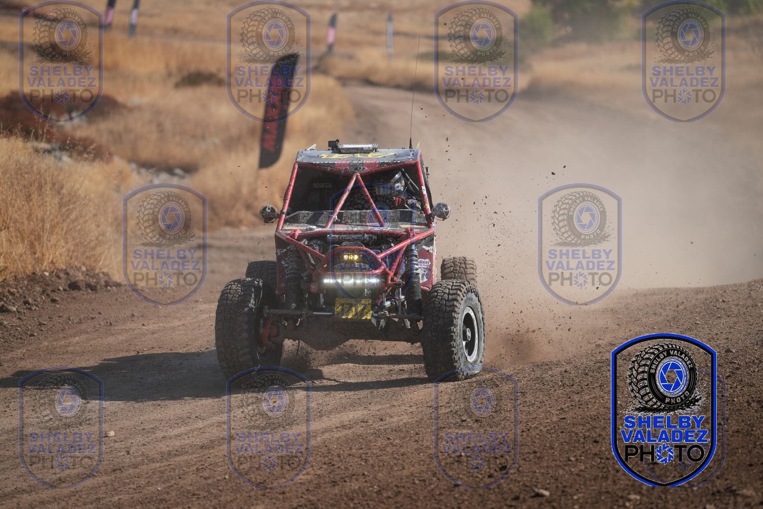 Red Ultra4 buggy on the dirt course with dust trailing behind