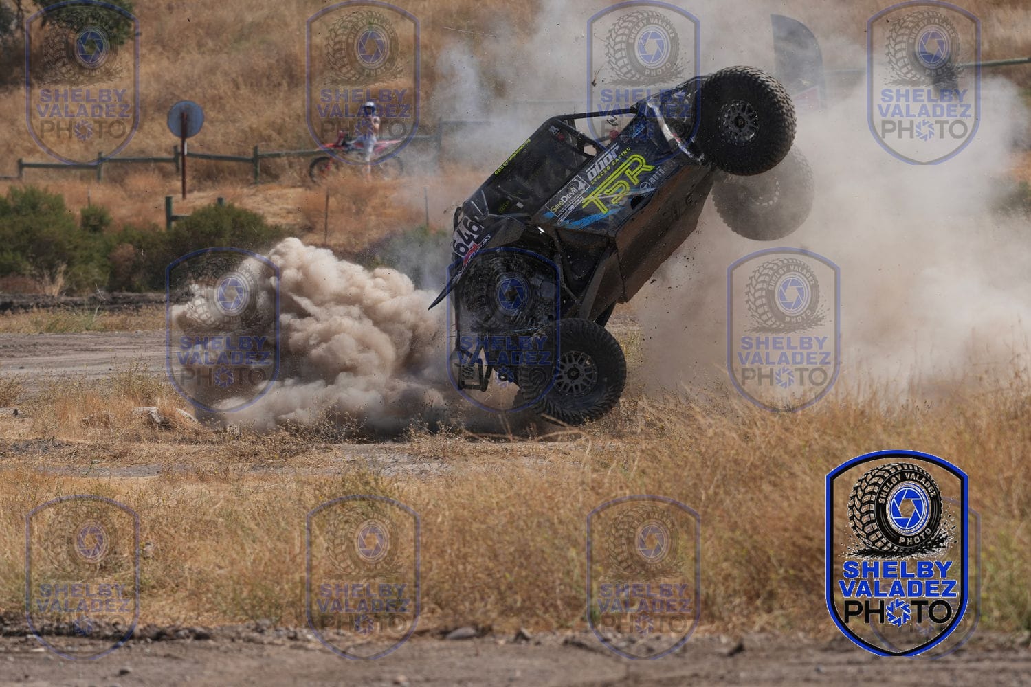 Green Ultra4 car kicking up a wall of dust through the rough